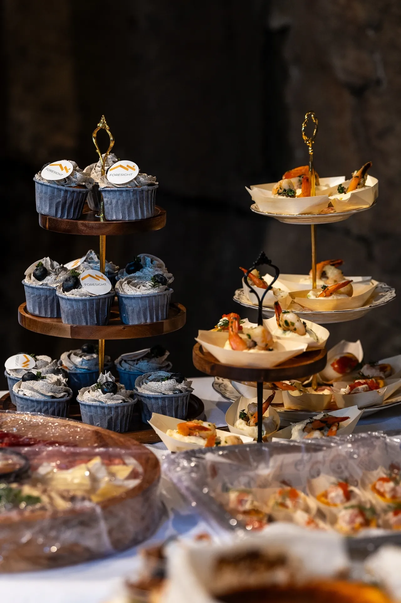 Elegant dessert display with blue cupcakes and assorted treats on tiered stands.