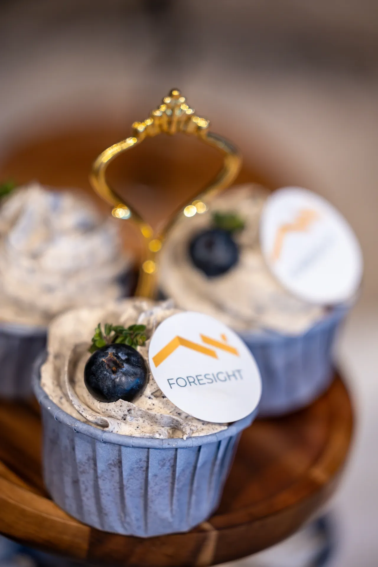 Elegant cupcakes topped with blueberries and custom logos.