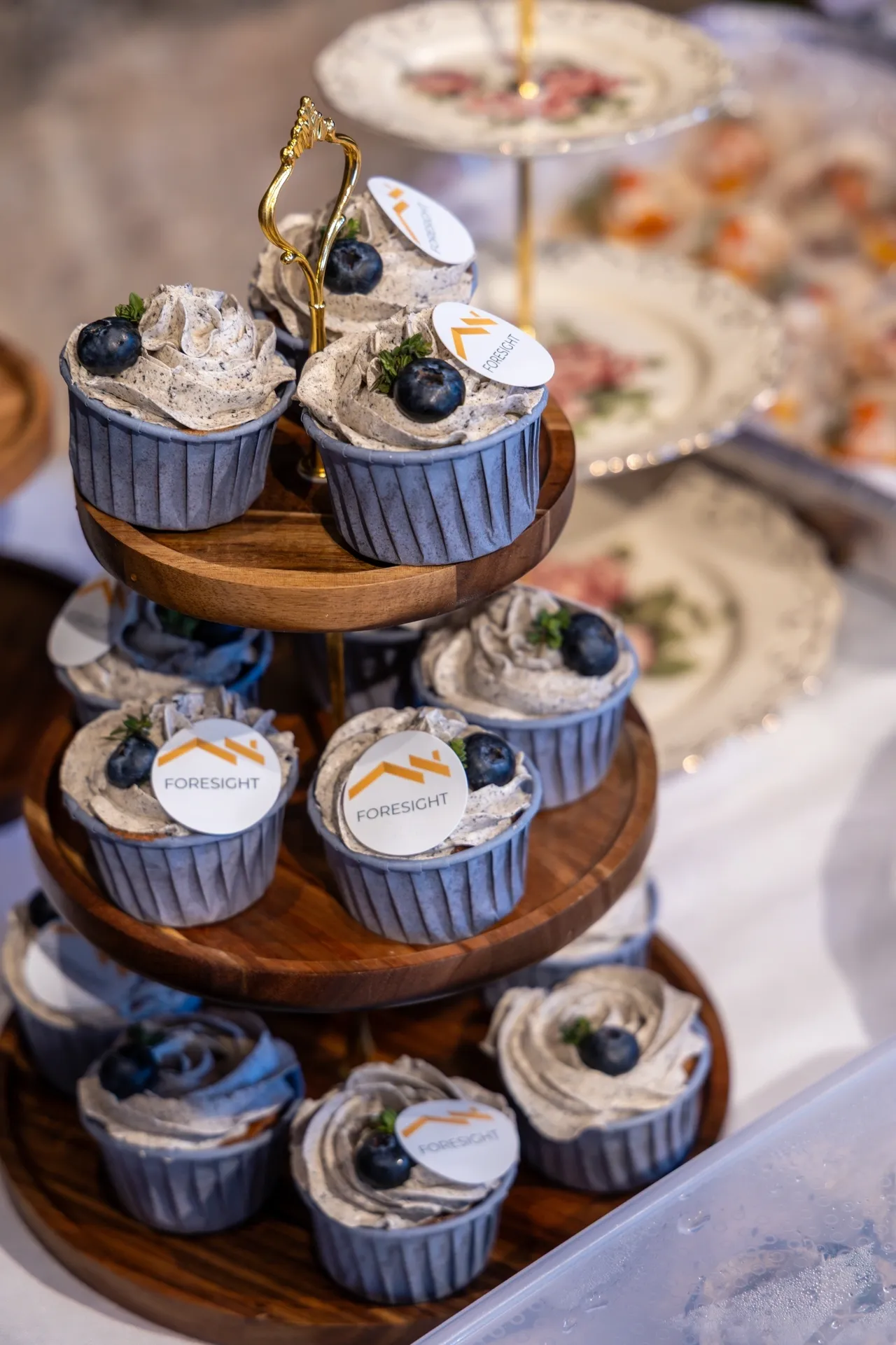 Blueberry cupcakes with creamy frosting on a wooden tiered stand.