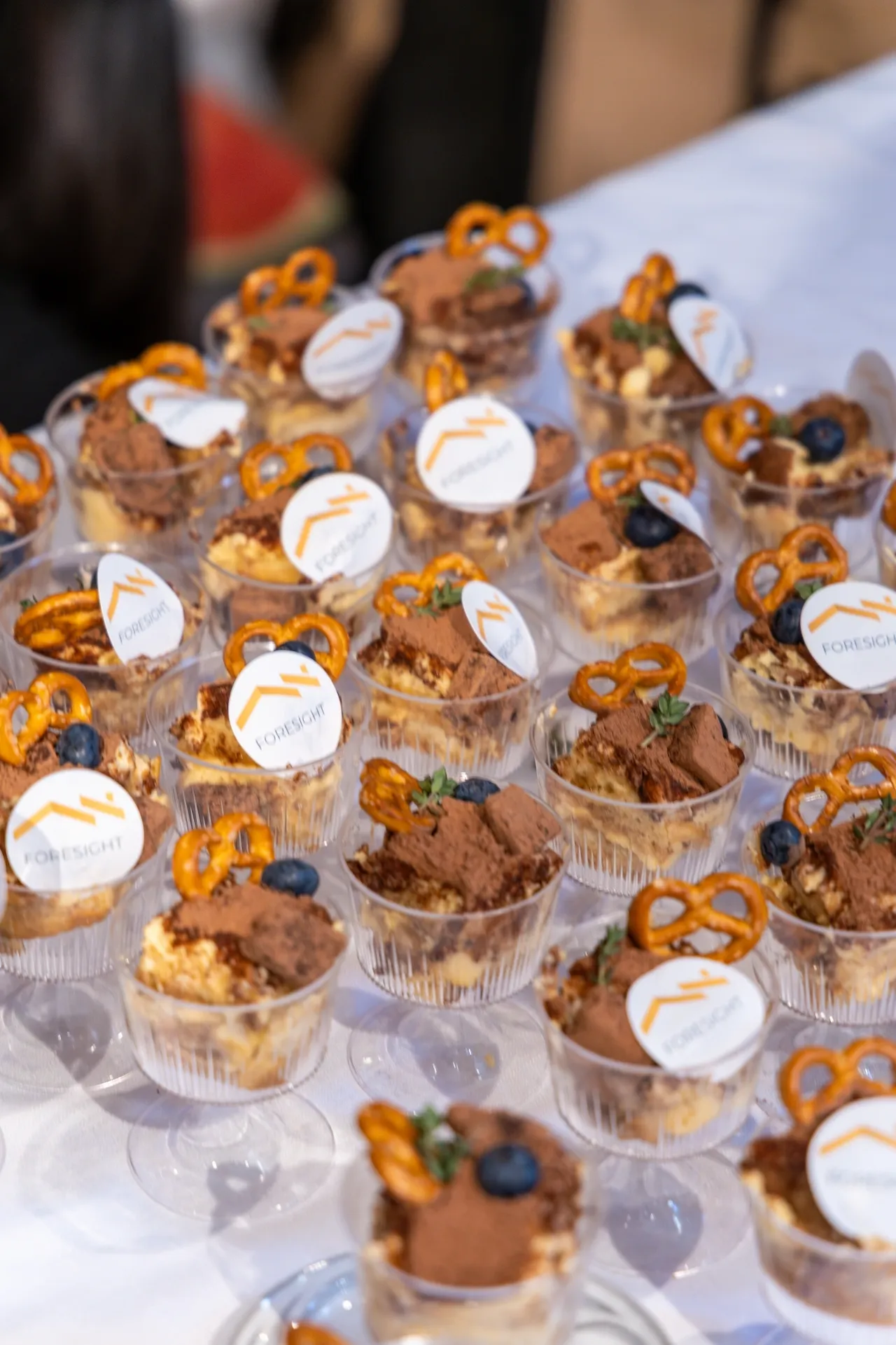 Assorted dessert cups with pretzels and chocolate toppings.