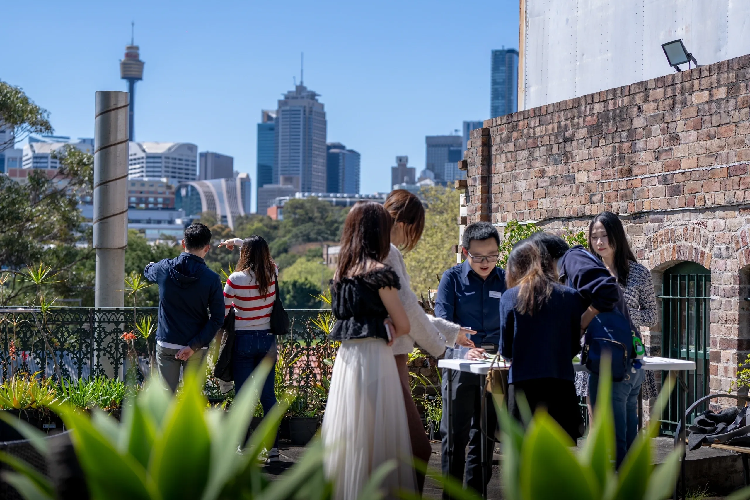 Guests mingle at an outdoor city rooftop event with skyline views.