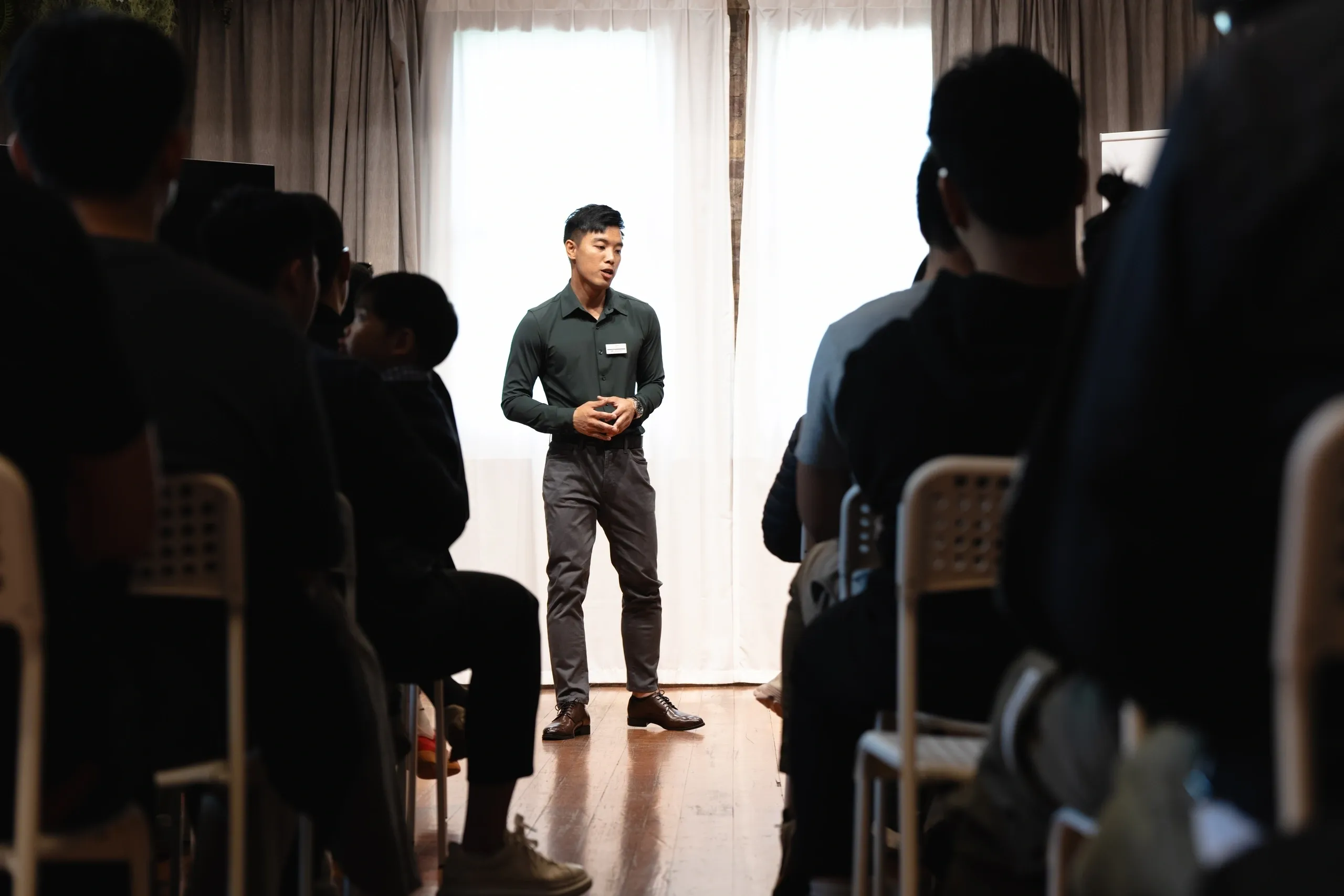 Man giving a speech to an attentive audience in a dimly lit room.