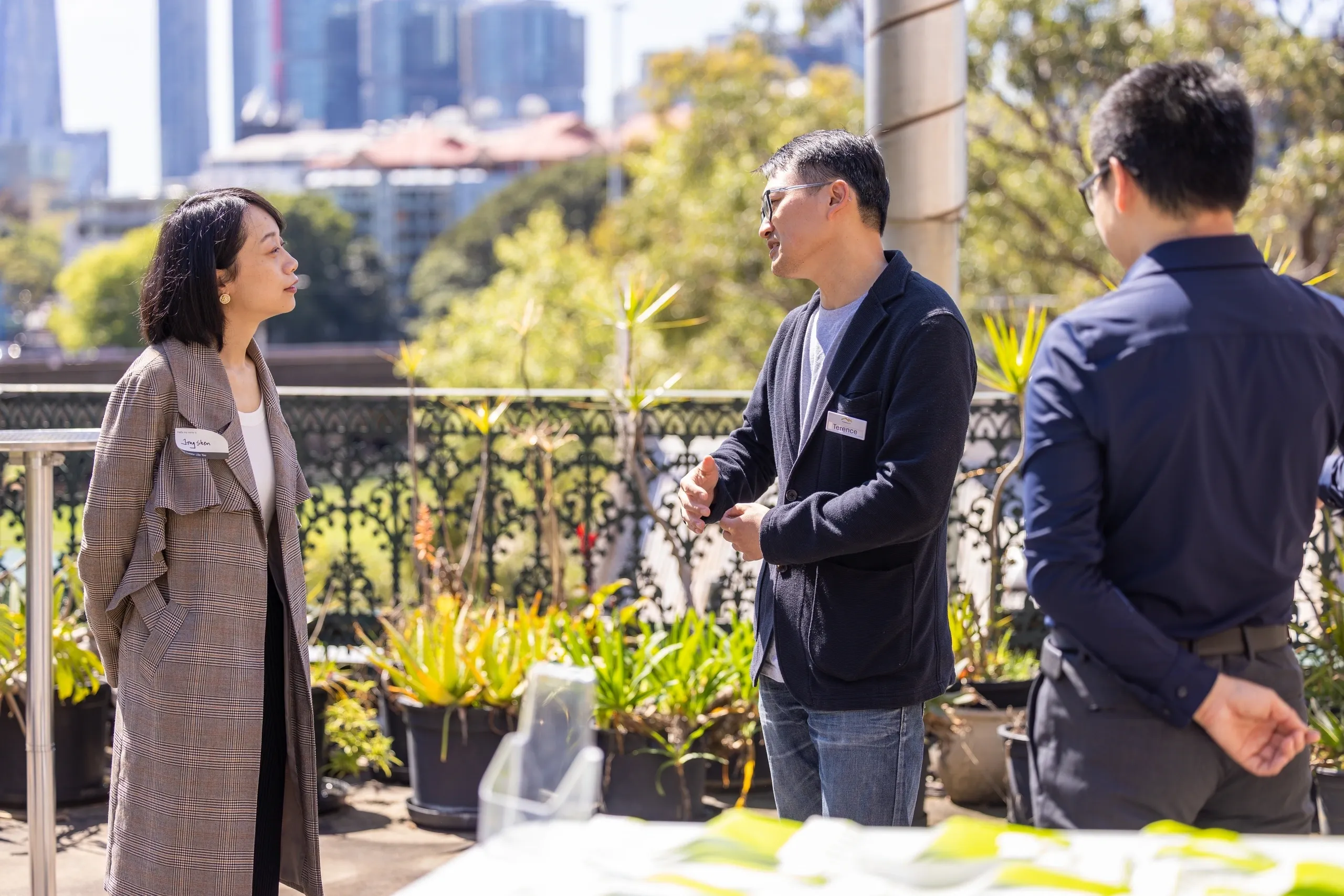 Three professionals engaged in a friendly outdoor conversation on a sunny day.