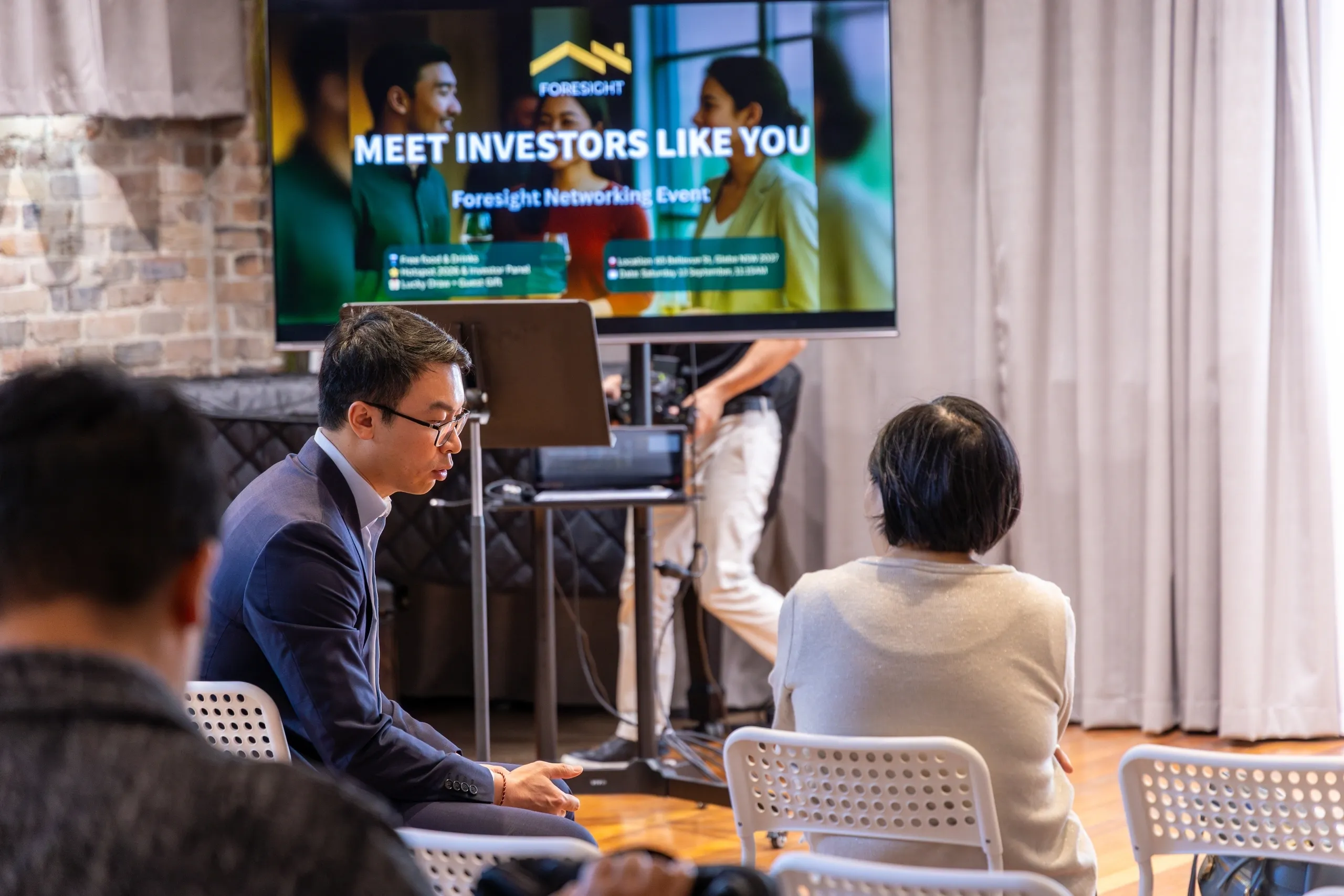 People attending a business networking event with a screen showing 'Meet Investors Like You'.