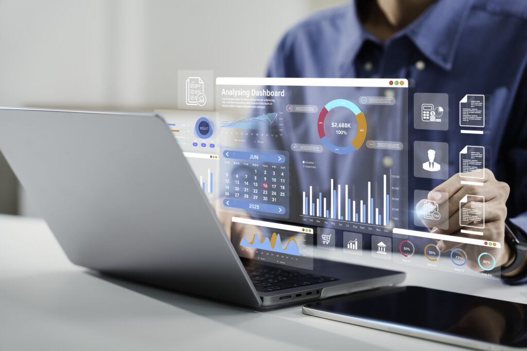 A person analyzing data and charts on a transparent digital interface above a laptop.